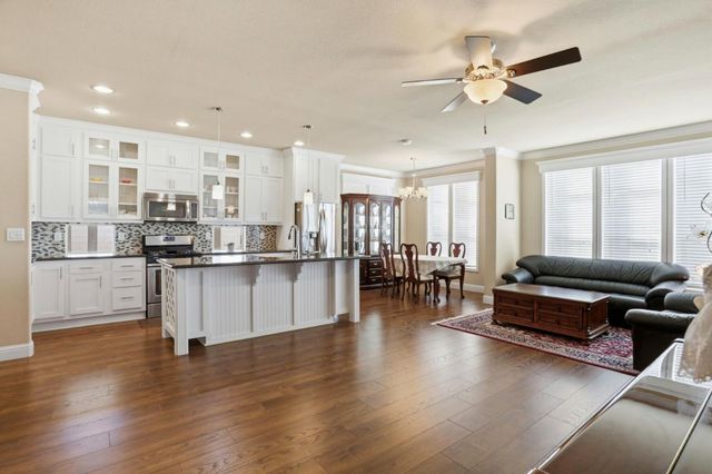 a living room with couches and kitchen view with wooden floor
