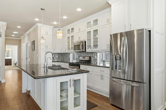 a kitchen with stainless steel appliances granite countertop a refrigerator a stove a sink and a microwave