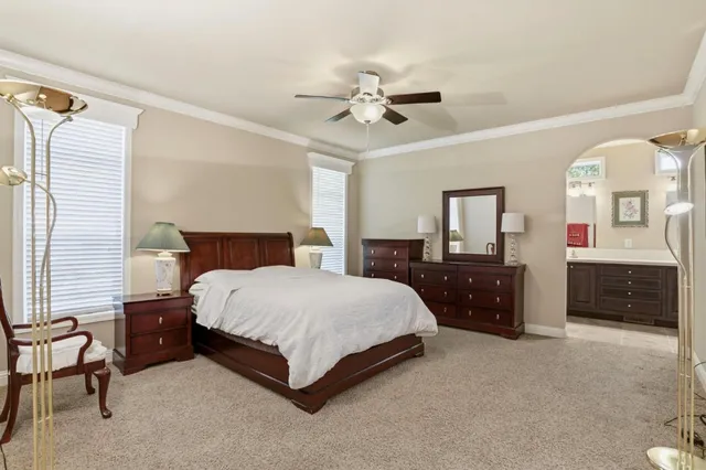 a spacious bedroom with a bed a dresser and a chandelier