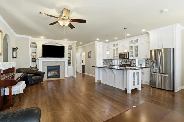a kitchen with stainless steel appliances kitchen island granite countertop a refrigerator a stove a sink dishwasher a dining table and chairs with wooden floor