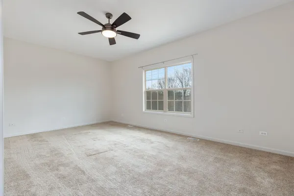 an empty room with ceiling fan and window