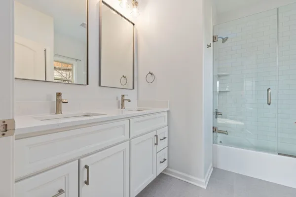 a bathroom with a double vanity sink a mirror and a bathtub