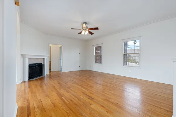 a view of an empty room with wooden floor fireplace and a window