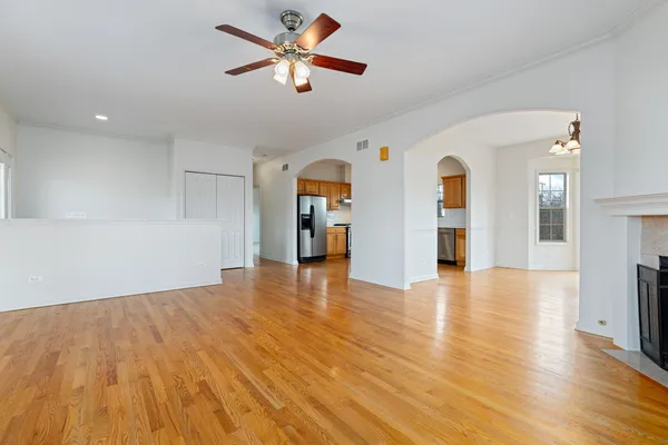 a view of empty room with wooden floor and fan
