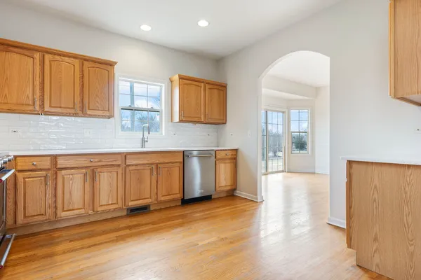 a kitchen with stainless steel appliances granite countertop a stove a sink and a refrigerator with wooden floors