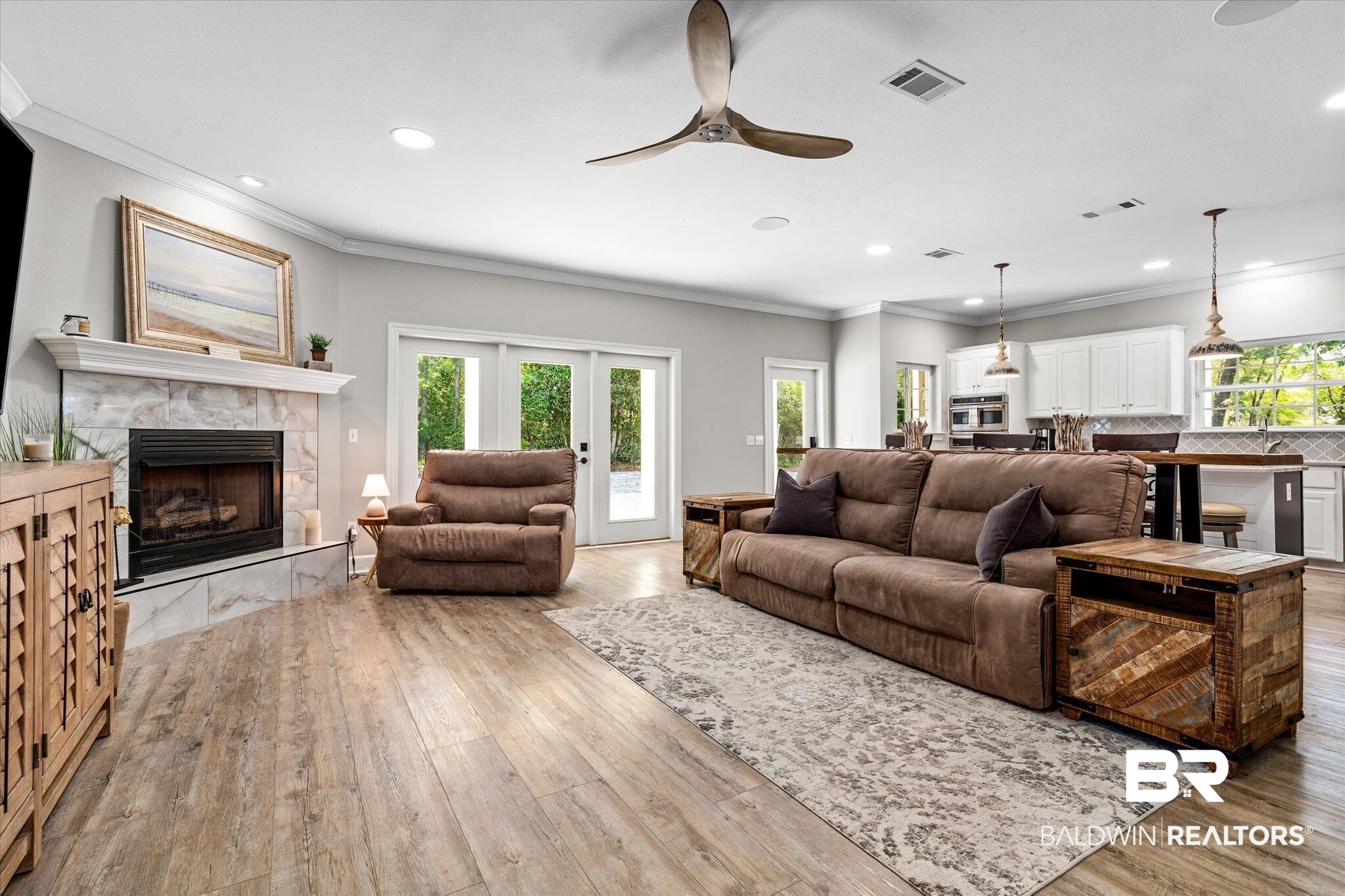 4947 Look Rook Road Orange Beach, AL 36561 - Photo 2 of 24 Living area with crown molding, ceiling fan, a tiled fireplace, and visible vents