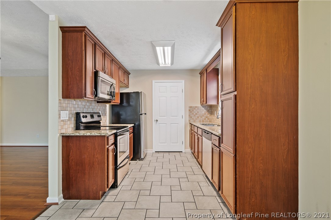 6568 Applewhite Road Fayetteville, NC 28304 - Photo 16 of 46 a kitchen with stainless steel appliances granite countertop a refrigerator and a stove top oven