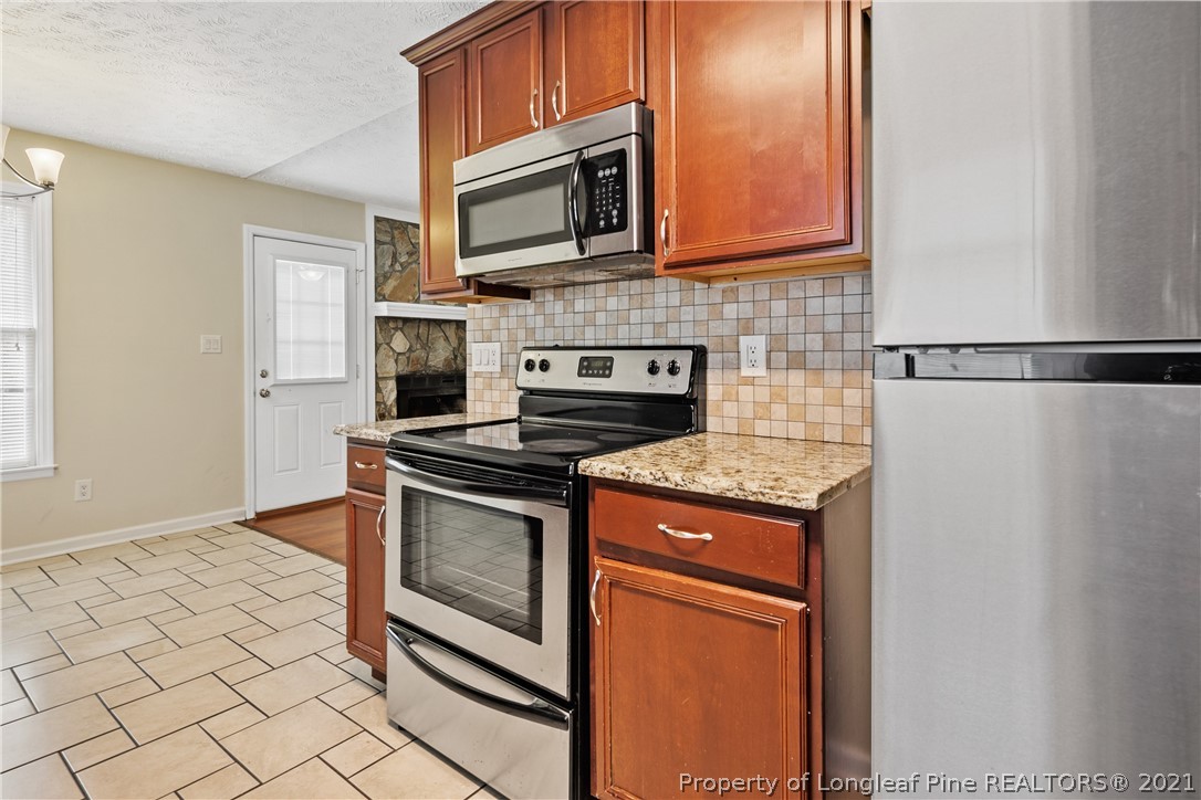6568 Applewhite Road Fayetteville, NC 28304 - Photo 21 of 46 a kitchen with granite countertop a stove top oven microwave and cabinets