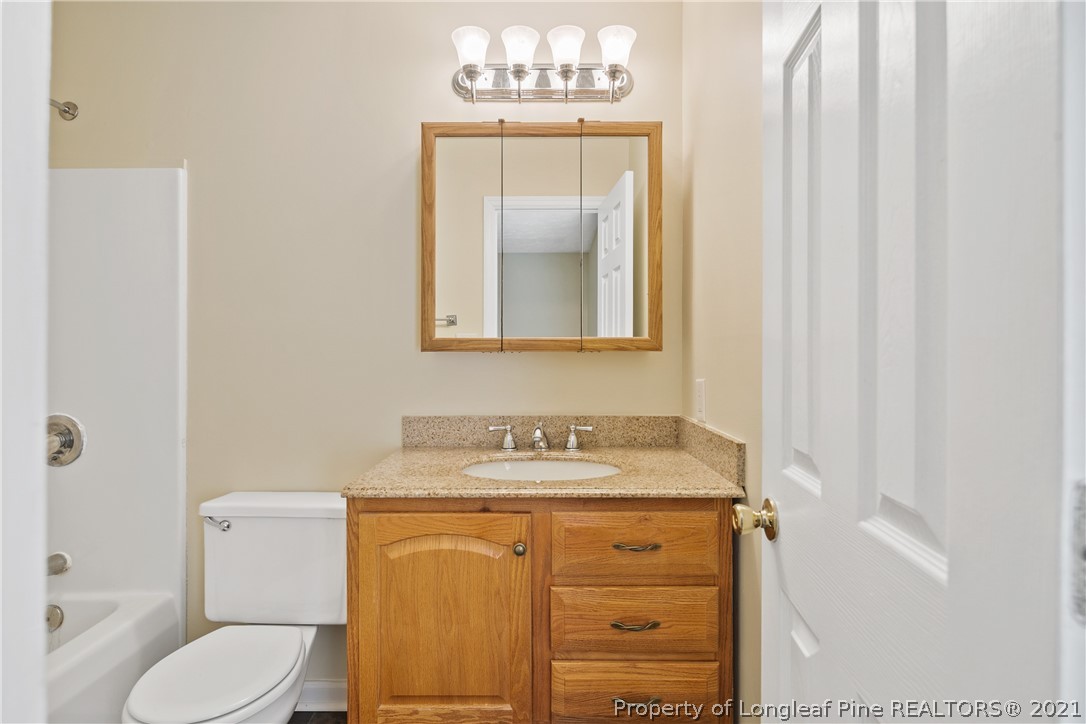 6568 Applewhite Road Fayetteville, NC 28304 - Photo 28 of 46 a bathroom with a granite countertop sink toilet and mirror