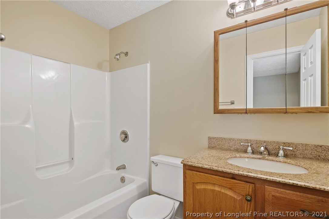 6568 Applewhite Road Fayetteville, NC 28304 - Photo 29 of 46 a bathroom with a granite countertop sink toilet and shower