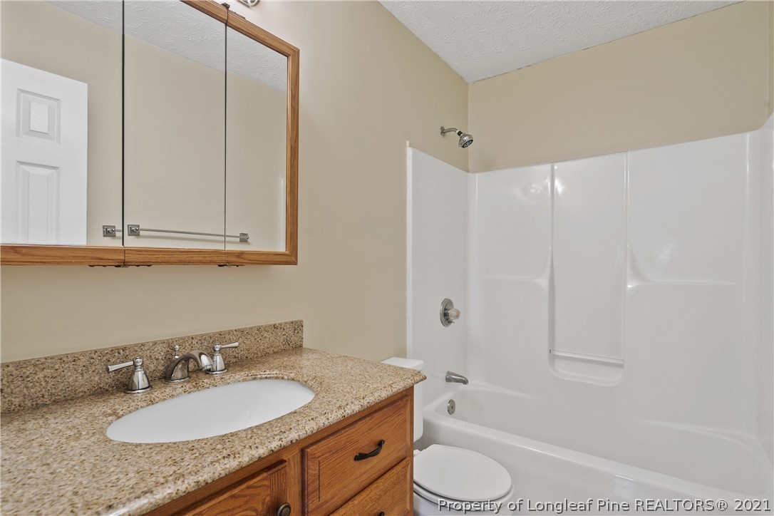 6568 Applewhite Road Fayetteville, NC 28304 - Photo 37 of 46 a bathroom with a granite countertop sink toilet and shower