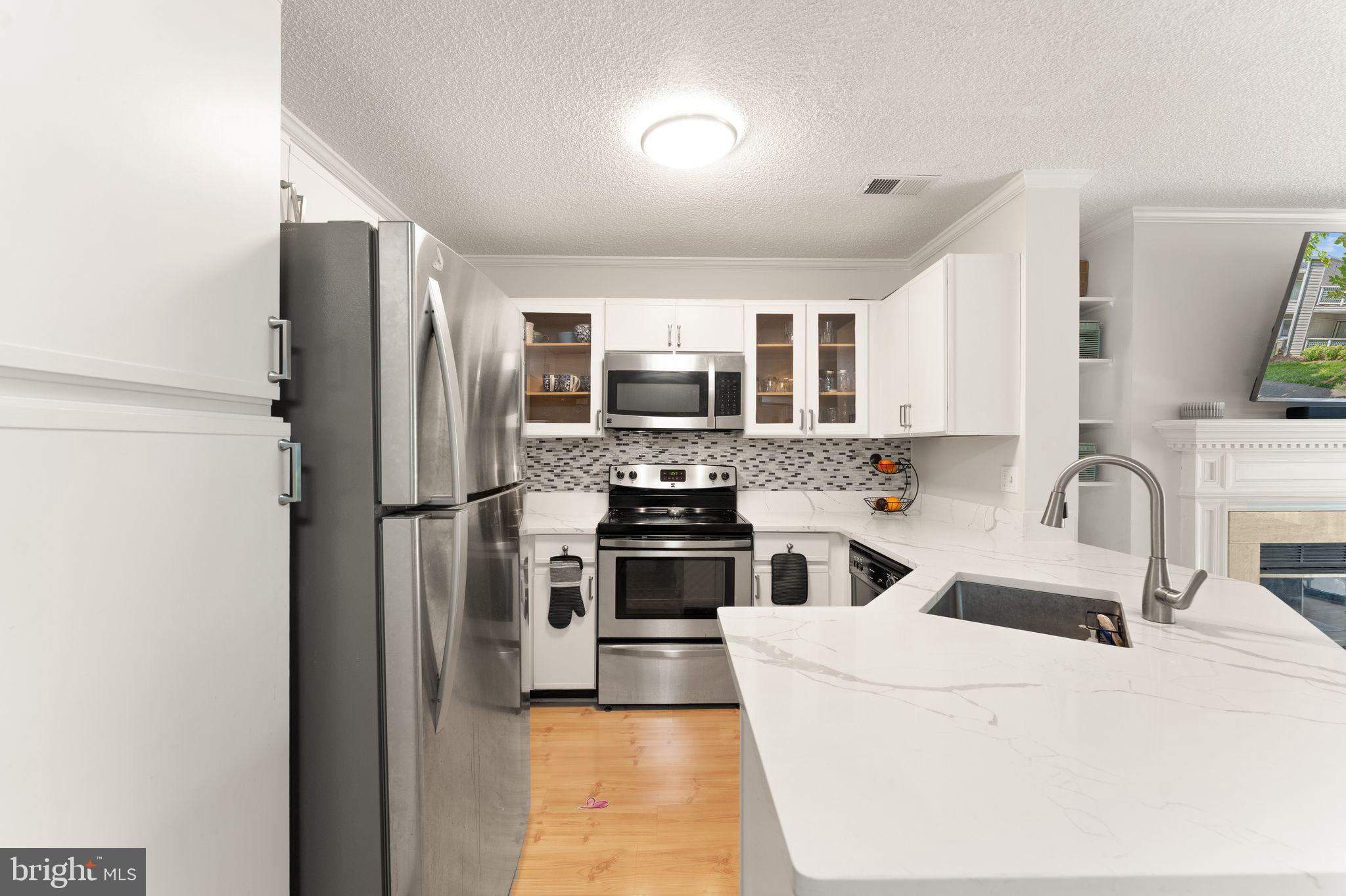 11741 Summerchase Circle, Unit A Reston, VA 20194 - Photo 17 of 32 a kitchen with stainless steel appliances a stove a sink a refrigerator white cabinets and a microwave