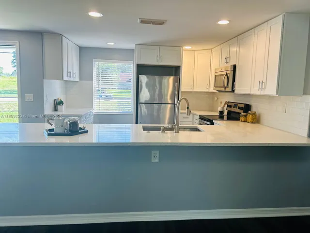 a kitchen with stainless steel appliances granite countertop a sink a stove and a refrigerator