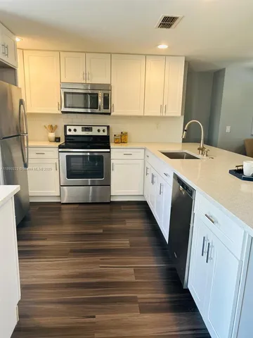 a kitchen with a refrigerator sink and cabinets
