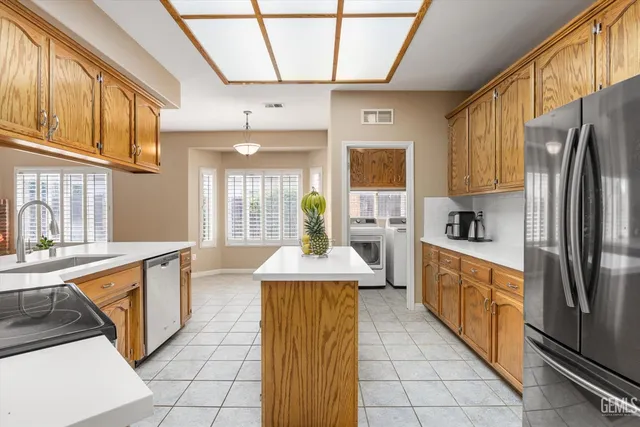 a kitchen with stainless steel appliances granite countertop a sink a stove a refrigerator cabinets and a microwave