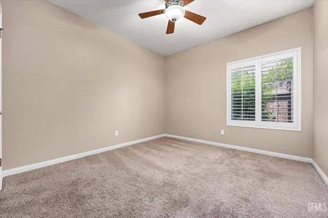 an empty room with a ceiling fan and carpet
