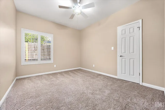 an empty room with a ceiling fan and carpet