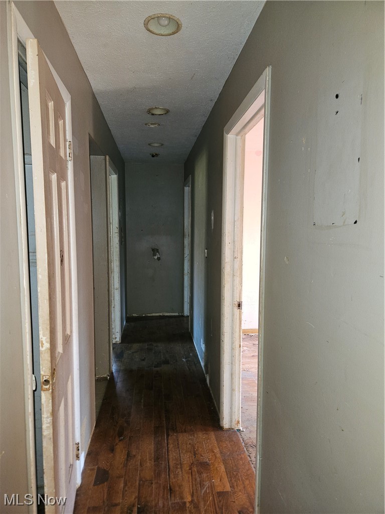 16940 Thompson Road Thompson, OH 44086 - Photo 7 of 30 Hallway featuring a textured ceiling and dark wood finished floors