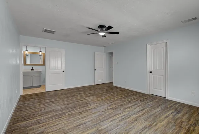 a view of an empty room and window a ceiling fan wooden floor and closet