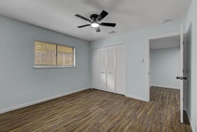 a view of empty room with wooden floor and ceiling fan