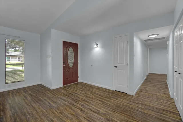 a view of an empty room with wooden floor and a window