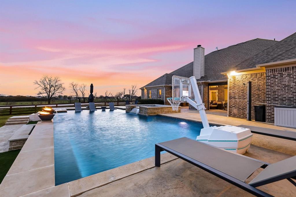 7751 Faught Road Northlake, TX 76226 - Photo 35 of 39 Outdoor living space featuring a swimming pool with integrated spa, a fire pit, extensive concrete and stone paving, and a brick-sided residence