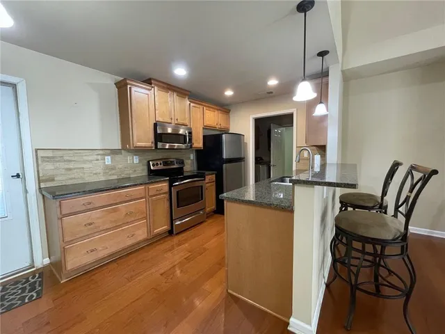 a kitchen with stainless steel appliances granite countertop a sink a stove a refrigerator and island