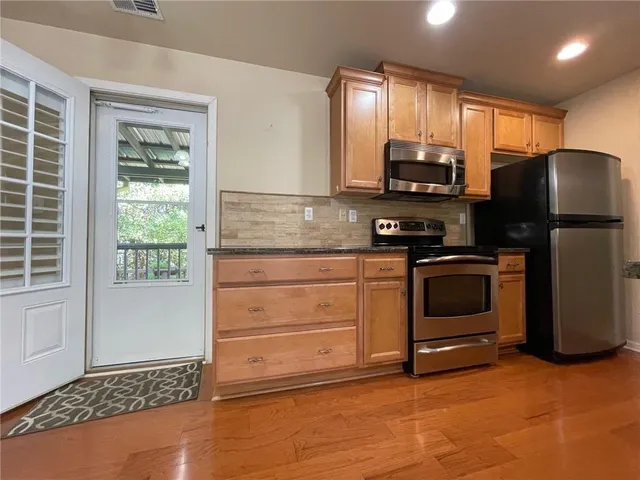 a kitchen with stainless steel appliances granite countertop a sink a stove and a wooden floors