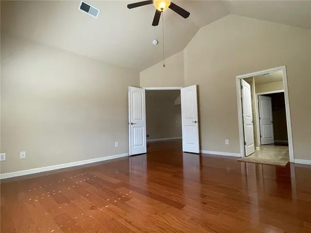 an empty room with wooden floor & windows