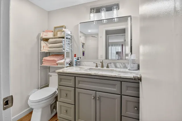 a bathroom with a granite countertop toilet sink and mirror