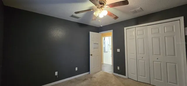 an empty room with closet and a chandelier fan