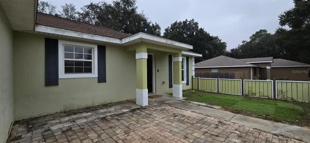 a view of a house with a yard and large tree