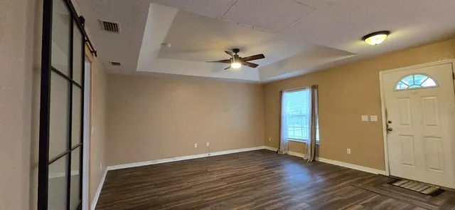 an empty room with wooden floor and a ceiling fan