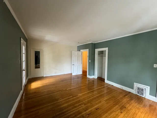 a view of an empty room with window and wooden floor