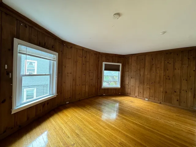 a view of an empty room with window and wooden floor