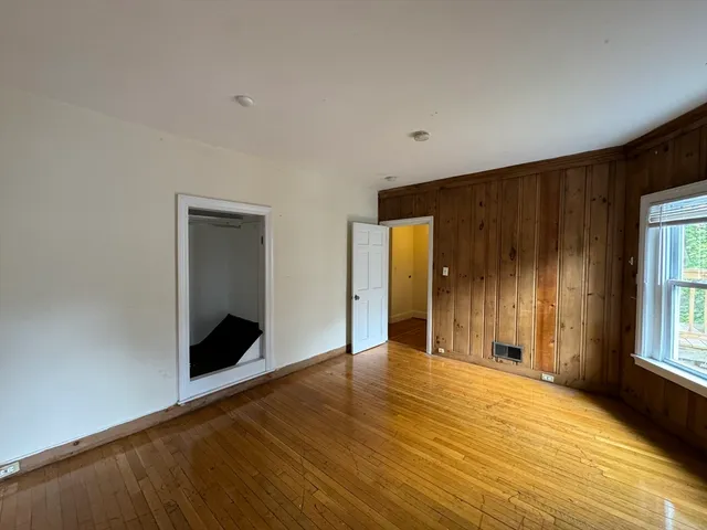 a view of an empty room with window and wooden floor