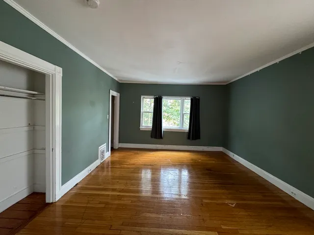 a view of empty room with window and wooden floor