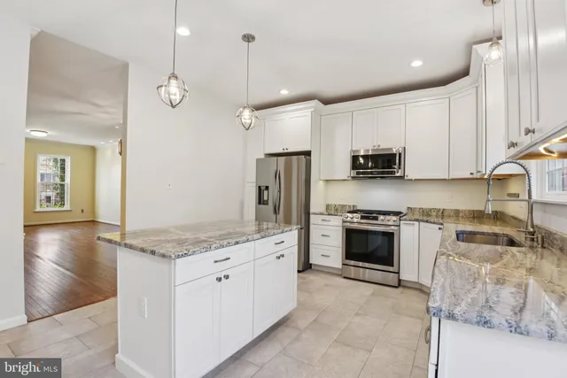 a large kitchen with stainless steel appliances granite countertop a stove a sink and a refrigerator