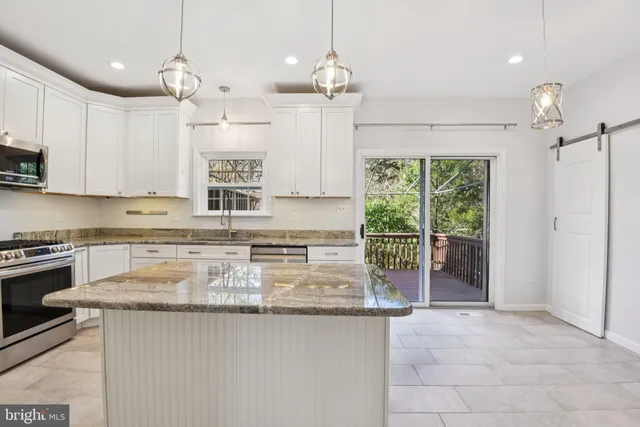 a kitchen with kitchen island granite countertop a stove a sink a oven and a counter top space