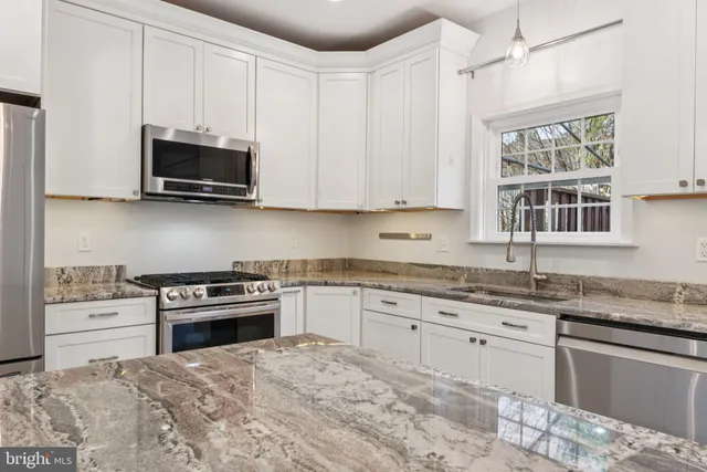 a kitchen with stainless steel appliances granite countertop a stove a sink and a microwave