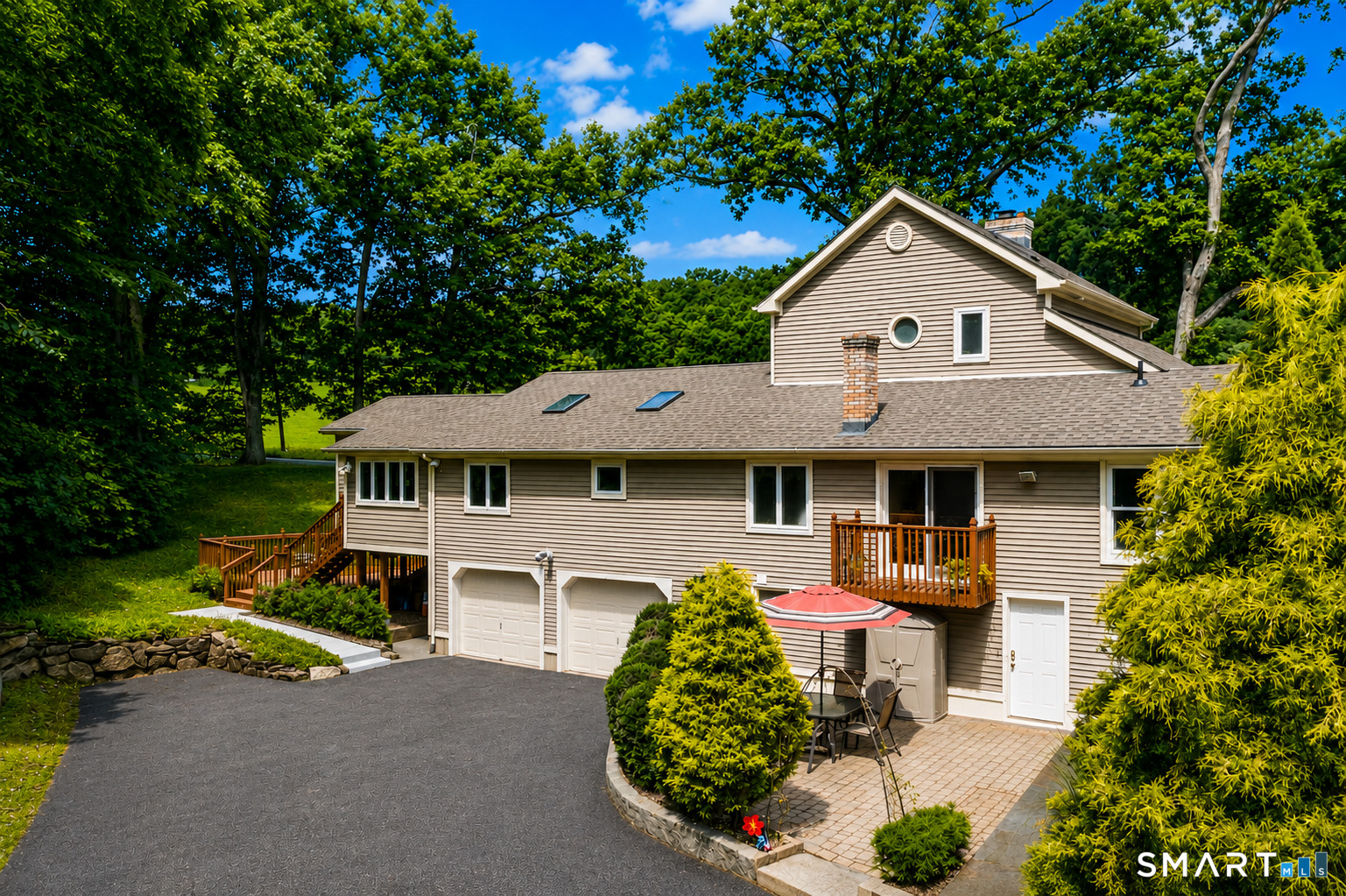 12 Ross Road Middlefield, CT 06481 - Photo 2 of 30 Rear view showcasing the home's thoughtful expansion, attached two-car garage, multiple outdoor access points and patio area, all surrounded by a private, wooded setting.
