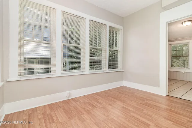 a view of an empty room with wooden floor and windows