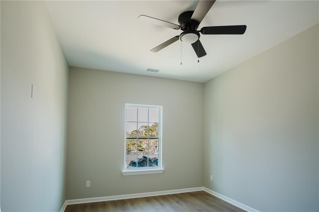 112 Neal Avenue Stockbridge, GA 30281 - Photo 17 of 19 an empty room with wooden floor and windows