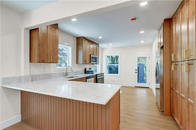 a kitchen with stainless steel appliances granite countertop a refrigerator a sink dishwasher and a oven with wooden floor