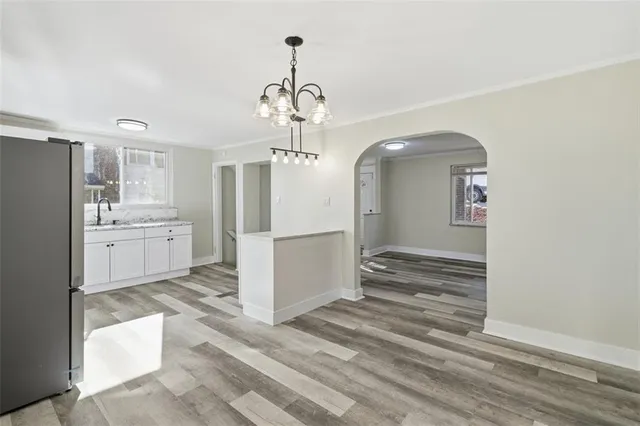 a view of a hallway with wooden floor and a kitchen space