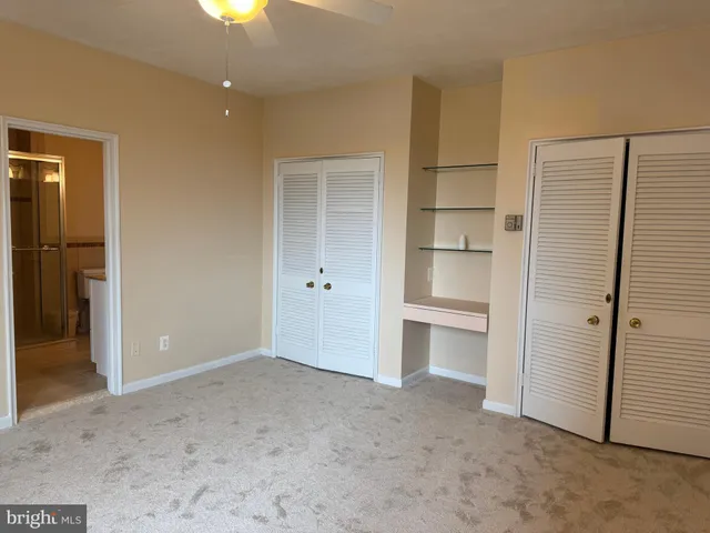 an empty room with a bathroom and a ceiling fan