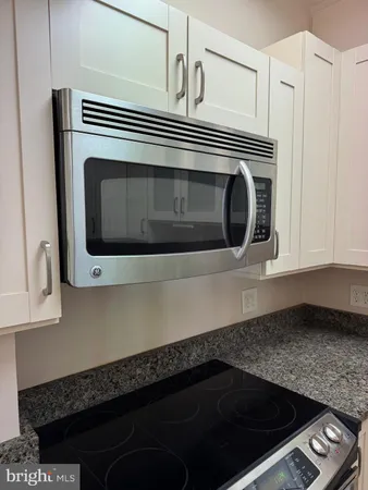 a kitchen with granite countertop white cabinets and stainless steel appliances