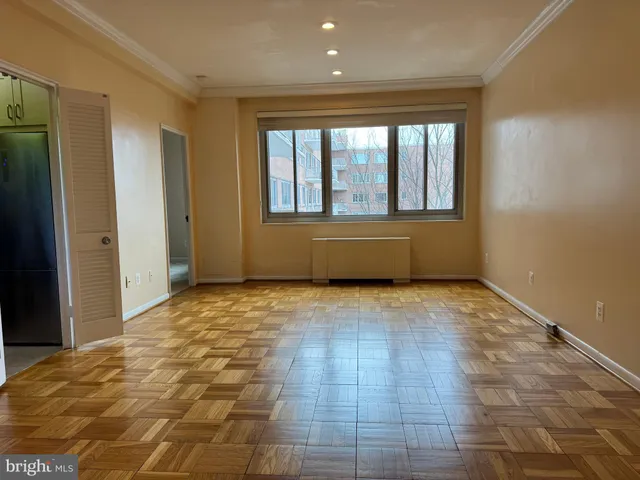 a view of an empty room with wooden floor and a window