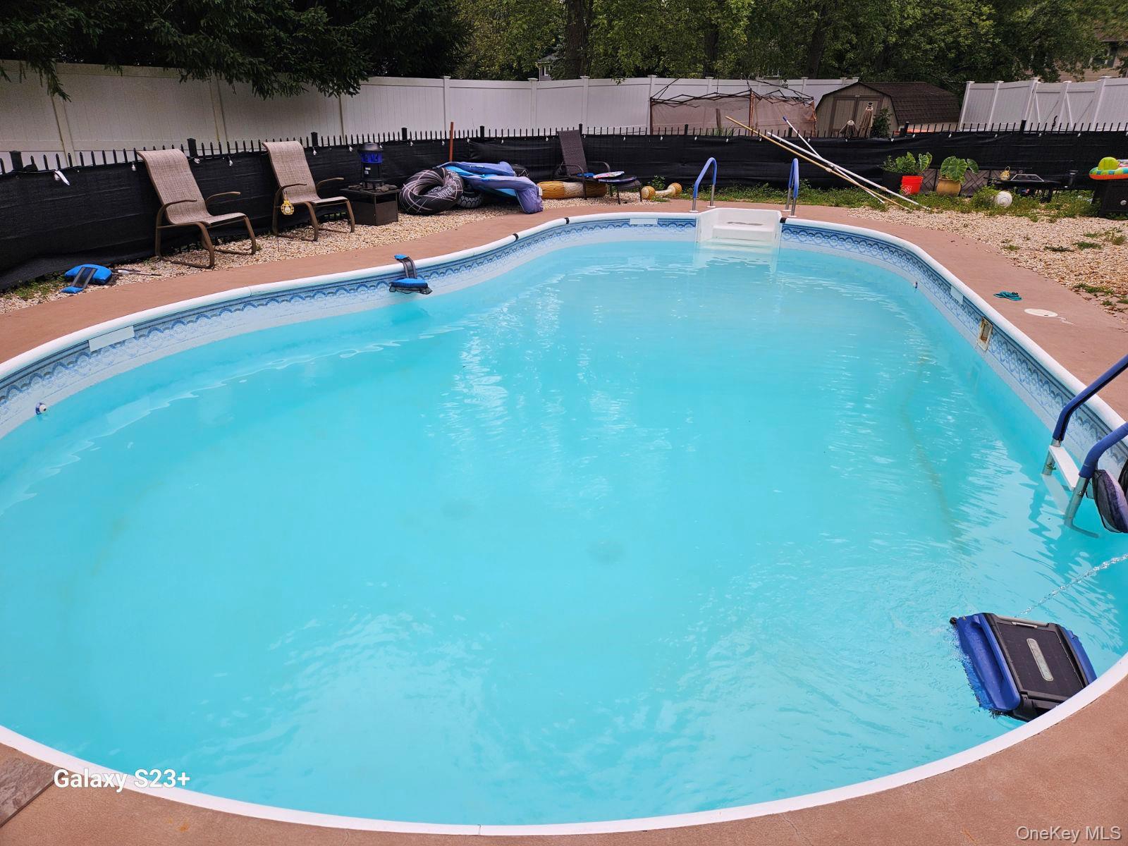 98 Sutton Park Road Poughkeepsie, NY 12603 - Photo 31 of 31 Kidney-shaped in-ground swimming pool featuring a patterned liner, white entry steps, and blue handrails