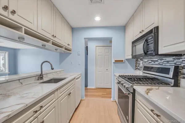 a kitchen with stainless steel appliances granite countertop a sink stove a refrigerator and cabinets with wooden floor